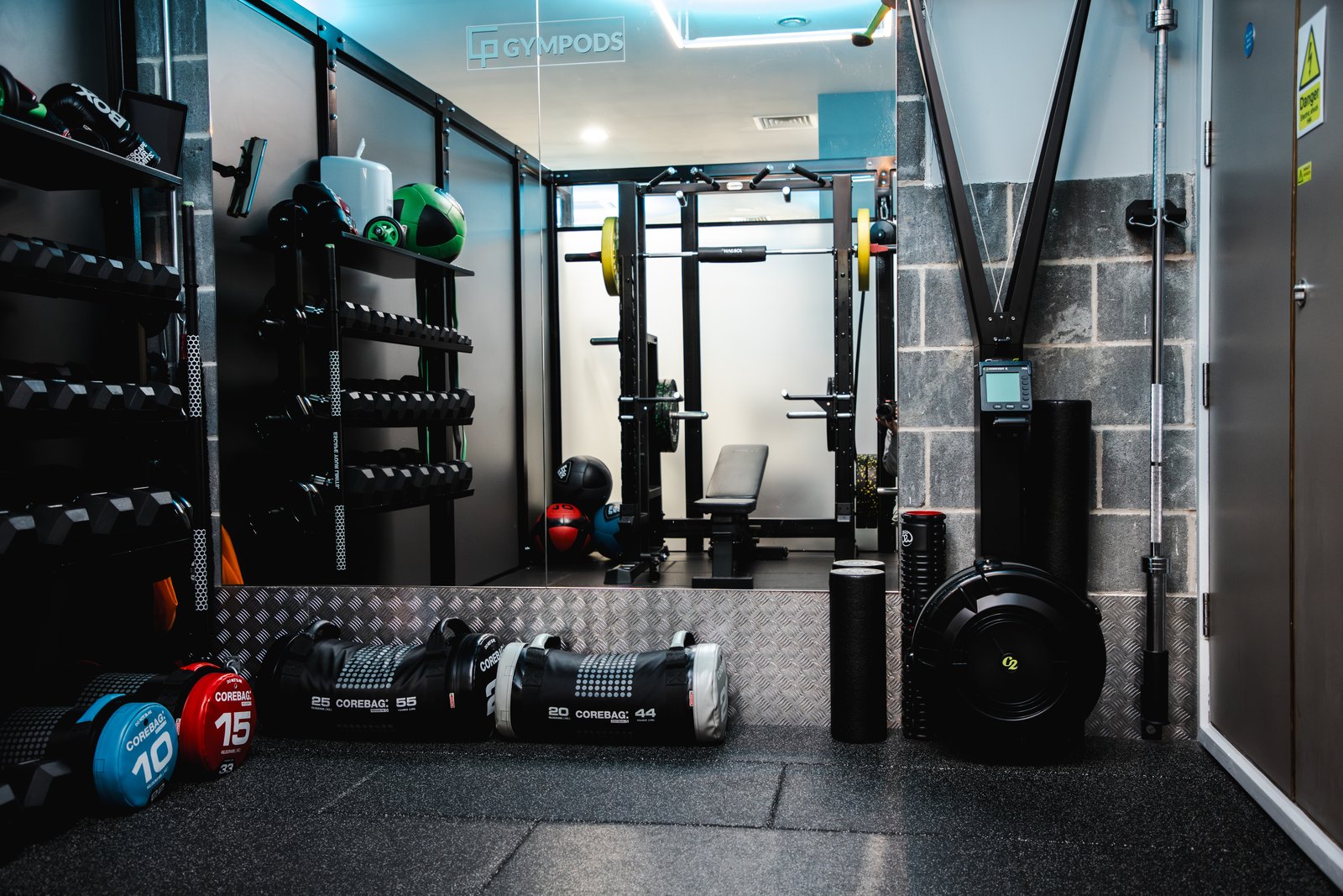Inside a private Power POD at GYMPODS Dalston — half rack, bench, dumbbells and functional kit in a fully equipped private gym space