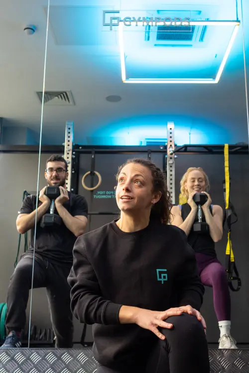 Two members training together with a personal trainer in a private Strength POD at GYMPODS Dalston